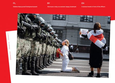 Photograph from the exhibition Belarus. road to freedom. the woman is kneeling in front of a row of soldiers. next to her, a woman wrapped with a historic Belarusian flag.